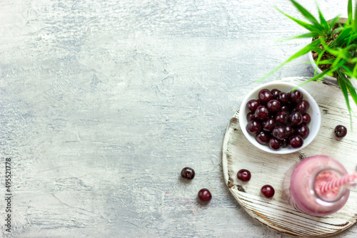 A bottle of cherry smoothies on a white background, cherries in bulk and in a plate. Morning summer breakfast