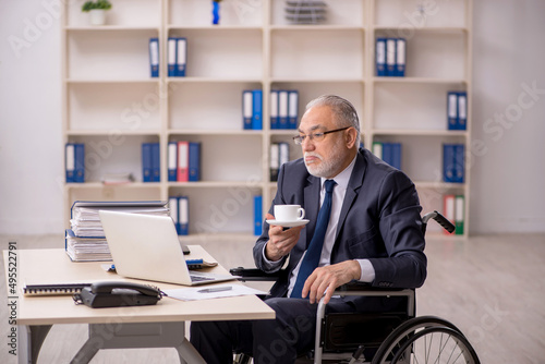 Old male employee in wheel-chair sitting at workplace © Elnur
