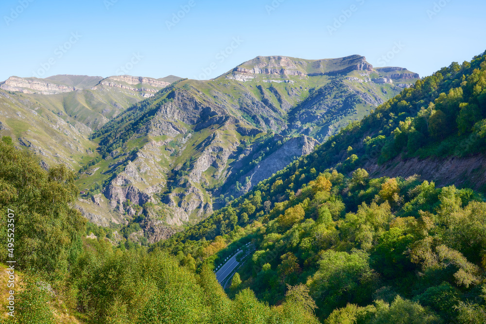 View from a height of a part of the road surrounded by beautiful mountains and forests. Bright colors in the mountains.