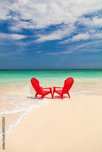 Ocean waves on sandy beach with red chairs
