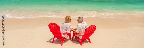Panoramic mature couple on beach by turquoise ocean