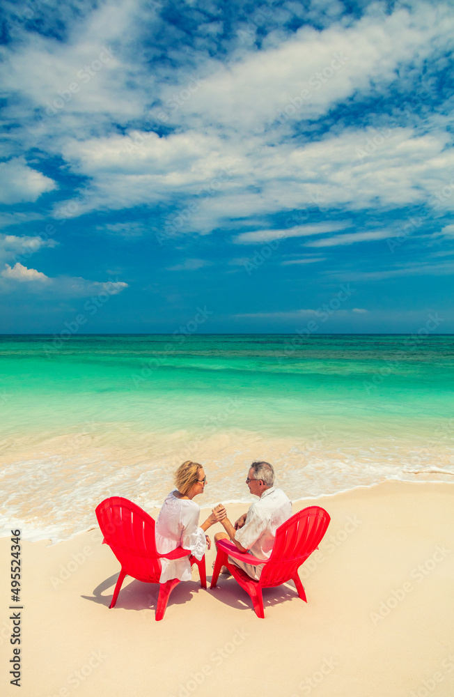 Mature couple on red chairs by ocean Bahamas Mature couple on red chairs by ocean Bahamas