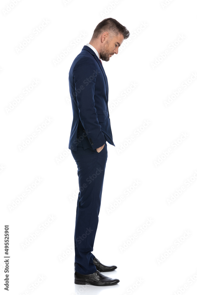 businessman looking down, feeling sad, holding his hands in pockets businessman looking down, feeling sad, holding his hands in pockets