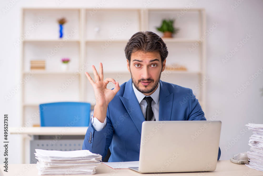 Young male employee and too much work in the office Young male employee and too much work in the office