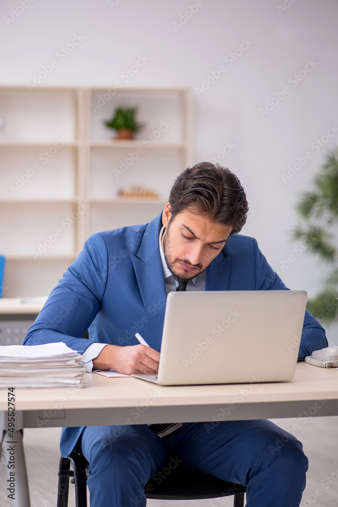 Young male employee and too much work in the office Young male employee and too much work in the office