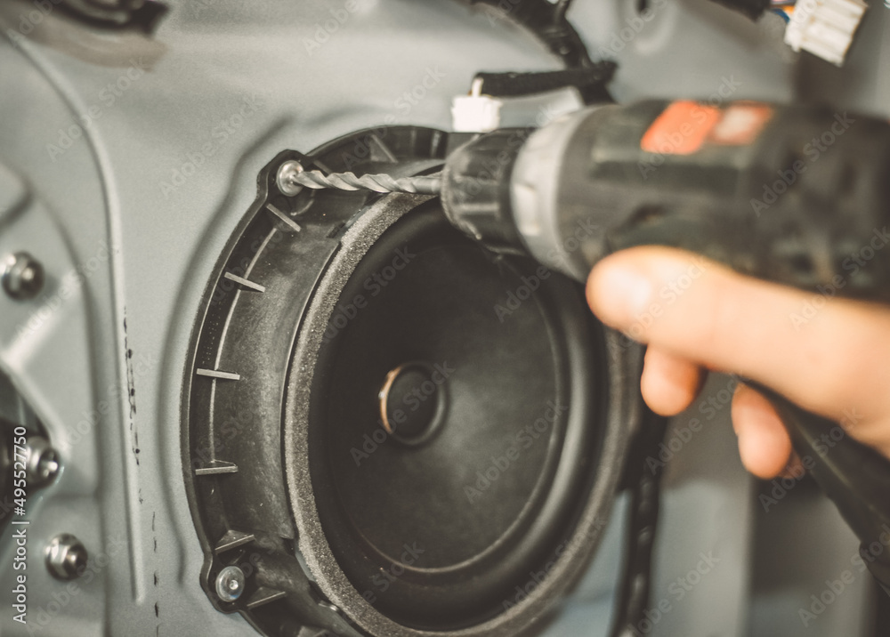 A car repairman repairs a car door. The car mechanic drills the car speaker out of the door. Work with a drill. A car repairman repairs a car door. The car mechanic drills the car speaker out of the door. Work with a drill.
