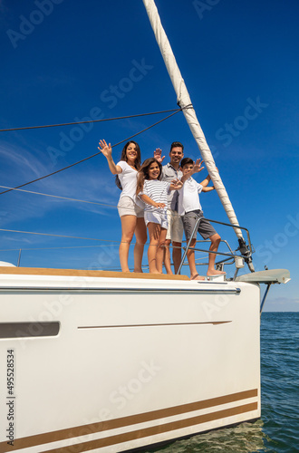 Hispanic family waving from bow of private yacht © Spotmatik