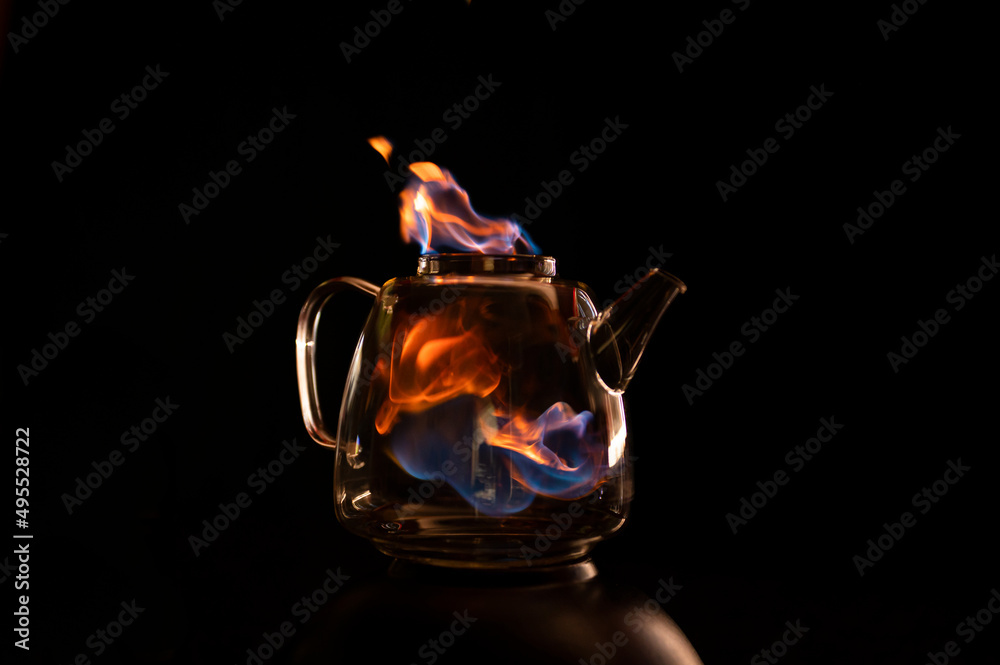 Fire within a see through glass tea pot showing beautiful orange and blue flames inferno giving the idea of substance or alcohol abuse.