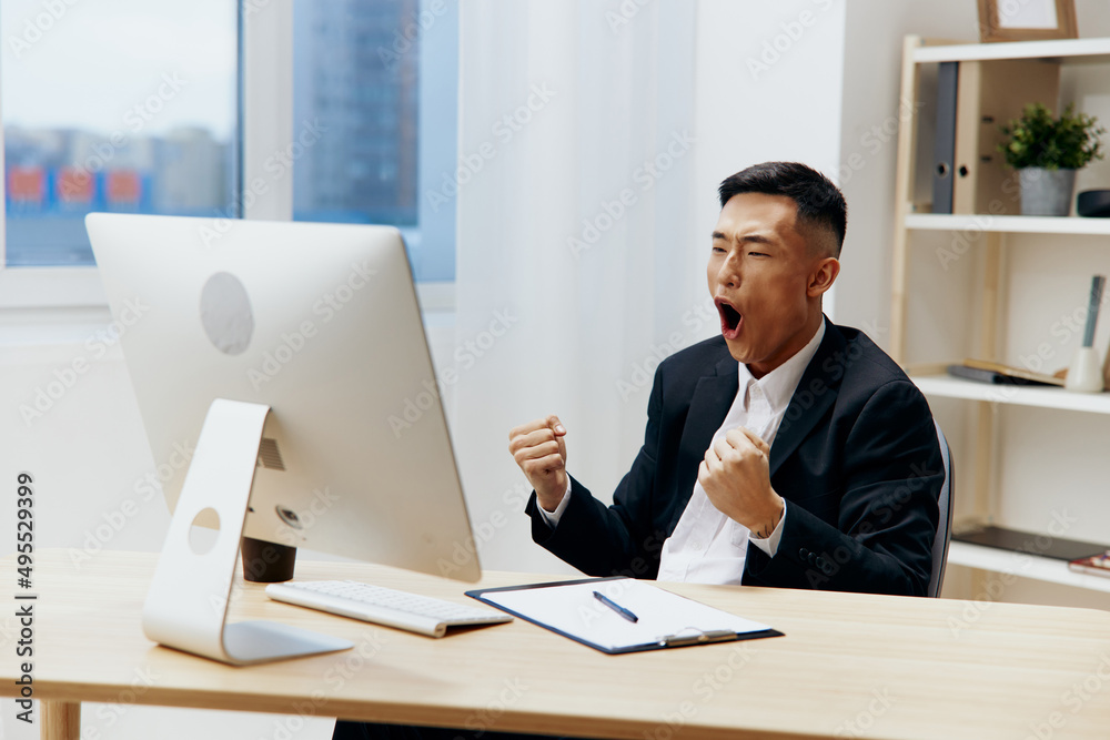 Asian man sitting at a desk in front of a computer technologies Asian man sitting at a desk in front of a computer technologies