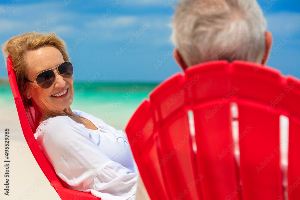 Smiling senior couple relaxing on chairs by ocean
