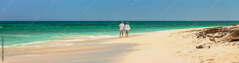 Panoramic tropical beach with couple walking along shoreline
