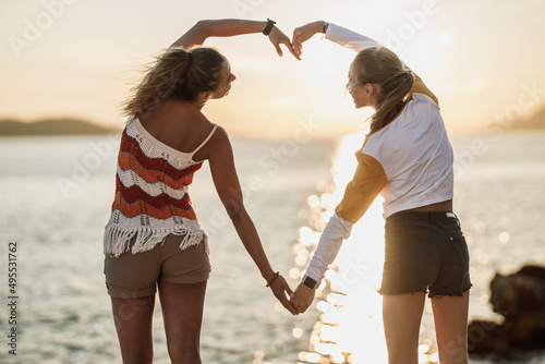 Two Women Making A Heart Shape With Their Hands And Enjoying Sunset At The Beach © milanmarkovic78