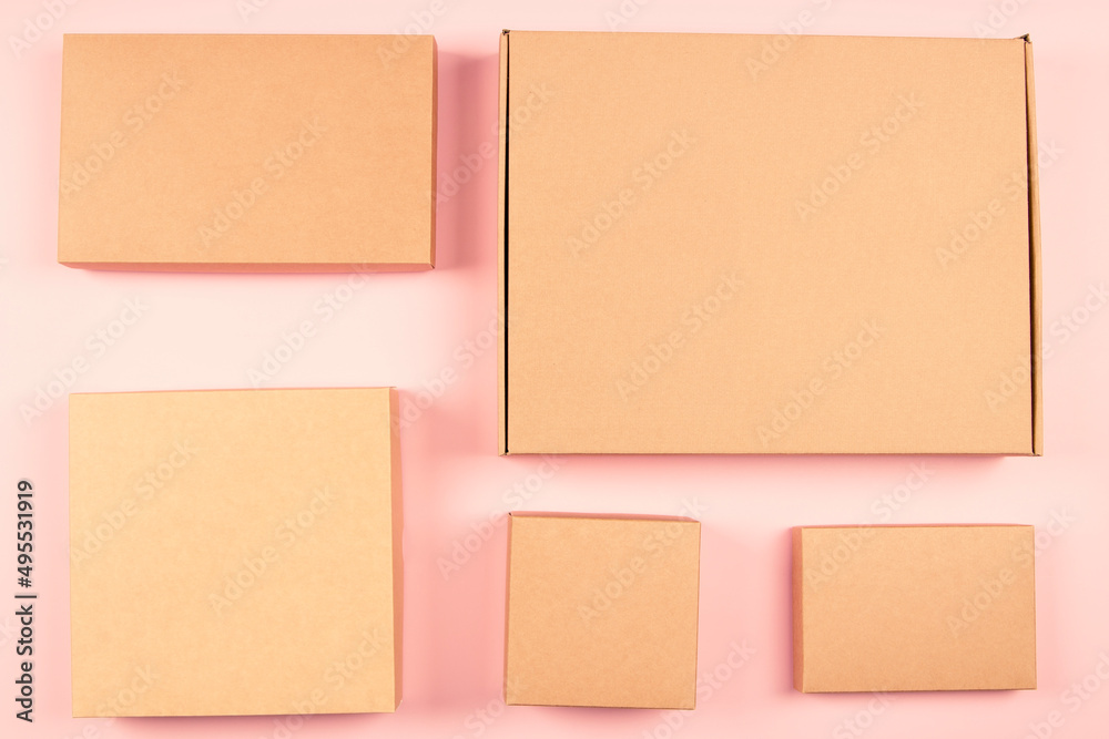 Group of brown cardboard boxes different size on pastel pink background. Mock up. Top view Group of brown cardboard boxes different size on pastel pink background. Mock up. Top view