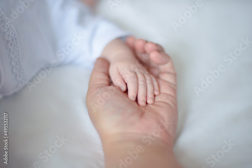 mom holds the hand of a newborn baby in her hand, mom's care and love