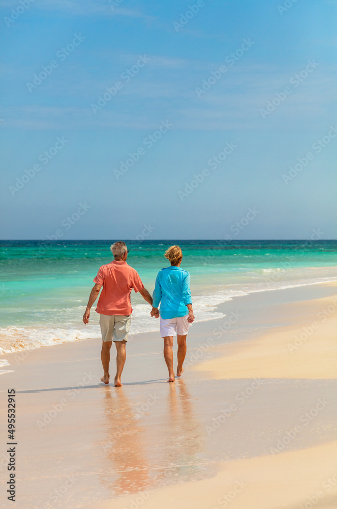 Travel loving mature couple walking on beach Bahamas