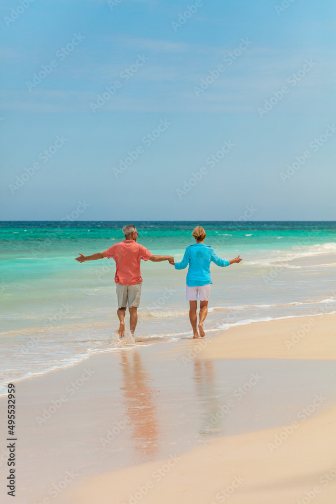 Retired couple paddling in ocean holding hands Bahamas