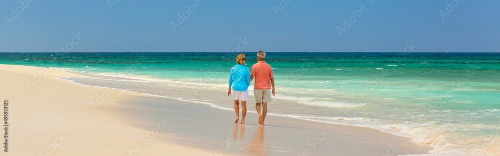Panoramic tropical beach with retired couple walking together Panoramic tropical beach with retired couple walking together