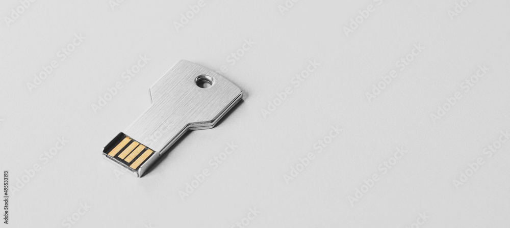 USB flash drive in the form of a metal key. White banner with usb flash memory in the form of a key, data security symbol USB flash drive in the form of a metal key. White banner with usb flash memory in the form of a key, data security symbol