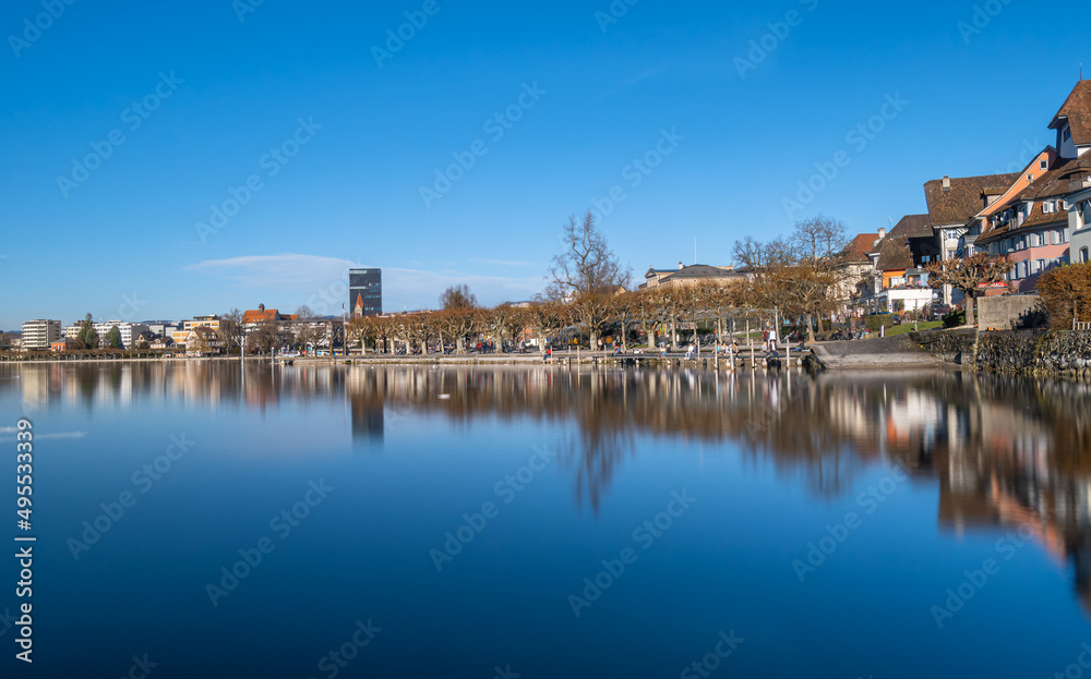 Sunny day and reflections of the city scape and older buildings situated by the lake