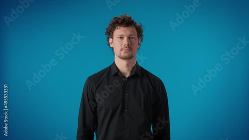 Portrait confident business man showing beheading gesture posing isolated on blue studio photo