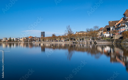 Sunny day and reflections of the city scape and older buildings situated by the lake