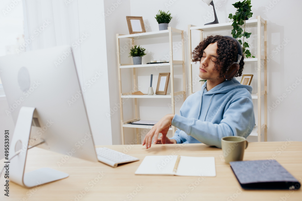 A young man sitting at a table in front of a computer music technologies