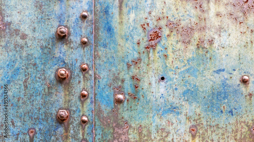 Grunge industrial background of worn metal with faced blue paint and rust spots joined by rivets and bolts with room for text