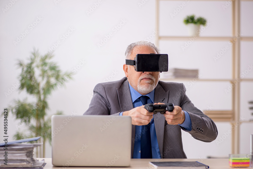 Old male employee enjoying virtual glasses at workplace Old male employee enjoying virtual glasses at workplace