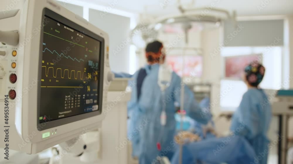 Modern medical operation room with monitor. Graphic lines on the screen of monitor to show heart ecg about the patient's condition during the operation. Heart rate monitor in hospital theater