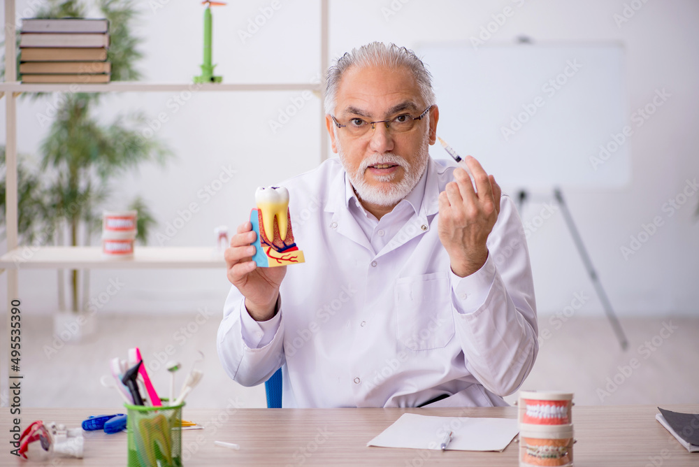 Old male dentist working in the clinic Old male dentist working in the clinic
