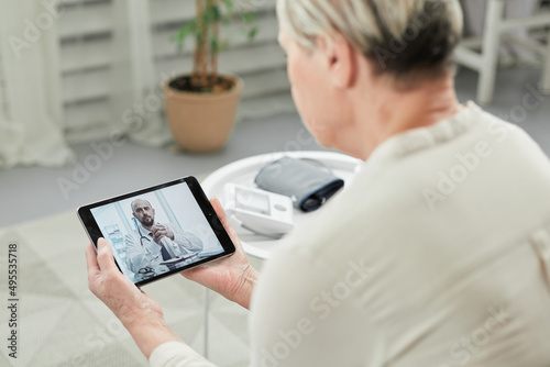 Telemedicine concept, old woman with tablet pc during an online consultation with her doctor in her living room. © Qwenergy
