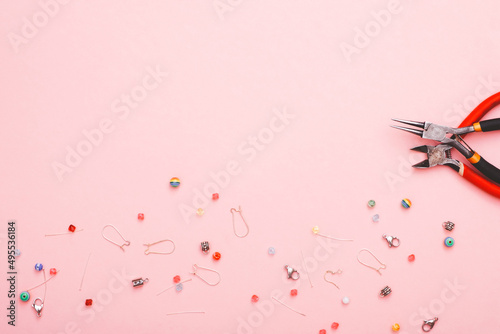 Jewellery making concept with beads and tools over pink paper background