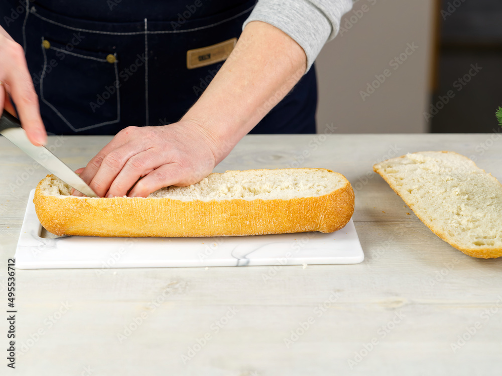 the cook cuts fresh ciabatta bread. Pulls out the pulp from the inside. Makes a base for stuffing bread. huge sandwich making process. close up