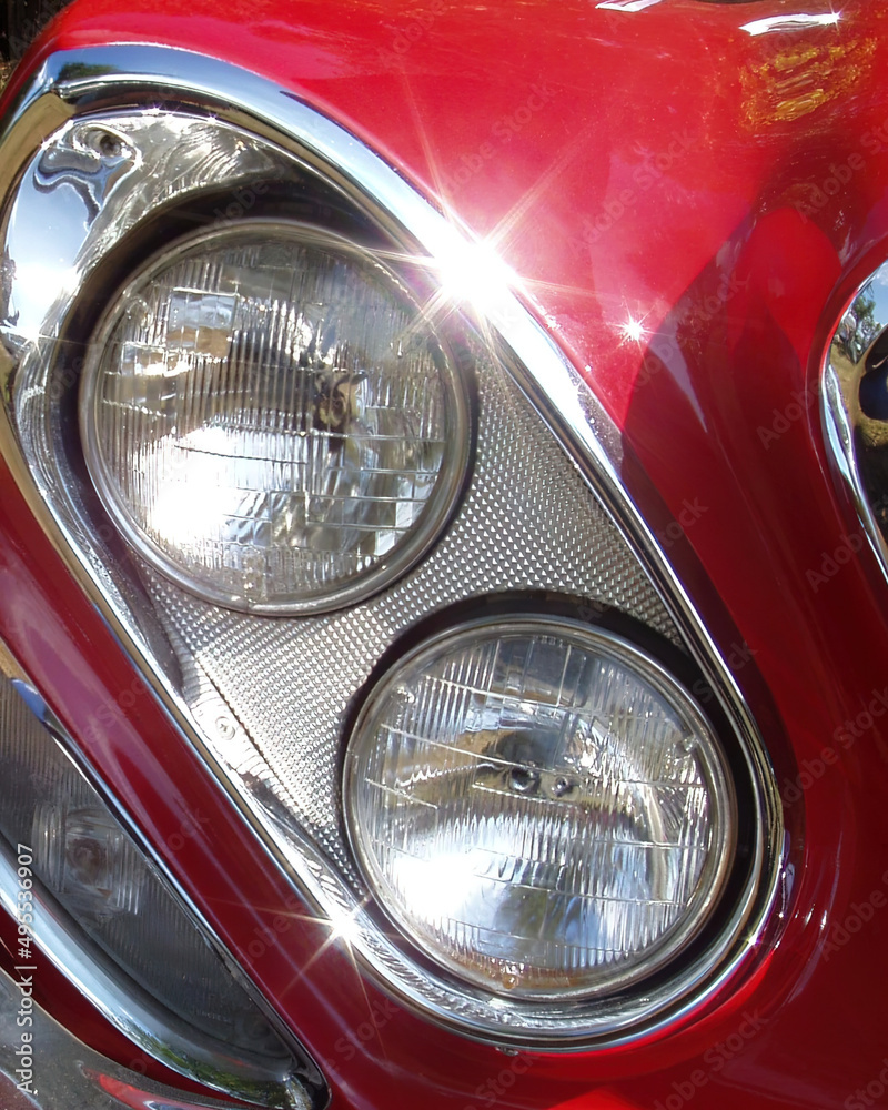 Detail of twin headlamps on a red classic car