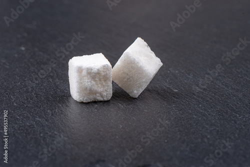 Cubes of white beet sugar refined on a stone background.
