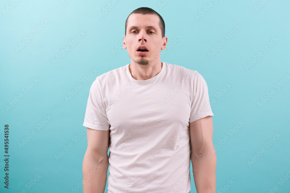 An unmotivated exhausted young man in a white t-shirt with open mouth on a blue background. Arm. Mid Adult. Boring. Bad. Boredom. Boy. Disturb. Lazy. Work. Goatee. Stare. Stress. Upset. Woke up An unmotivated exhausted young man in a white t-shirt with open mouth on a blue background. Arm. Mid Adult. Boring. Bad. Boredom. Boy. Disturb. Lazy. Work. Goatee. Stare. Stress. Upset. Woke up