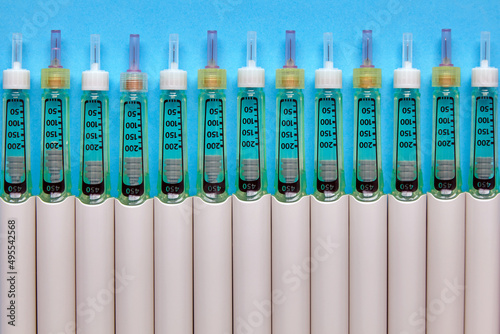 Syringe pens with insulin lined up in a row on a blue background