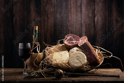 Fotografia Assorted homemade cheese, salumi on wooden table with a wooden background
