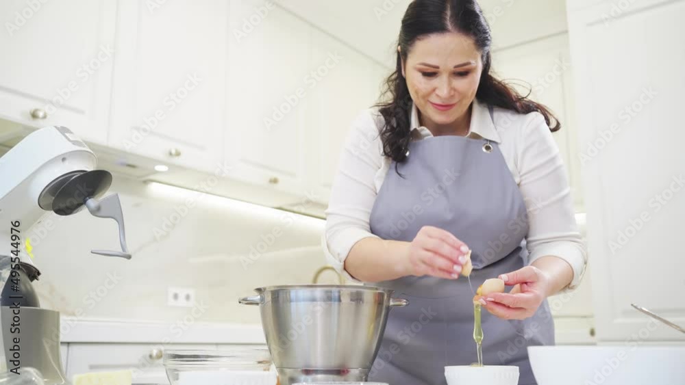 A woman breaks an egg and separates yolks from proteins A woman breaks an egg and separates yolks from proteins