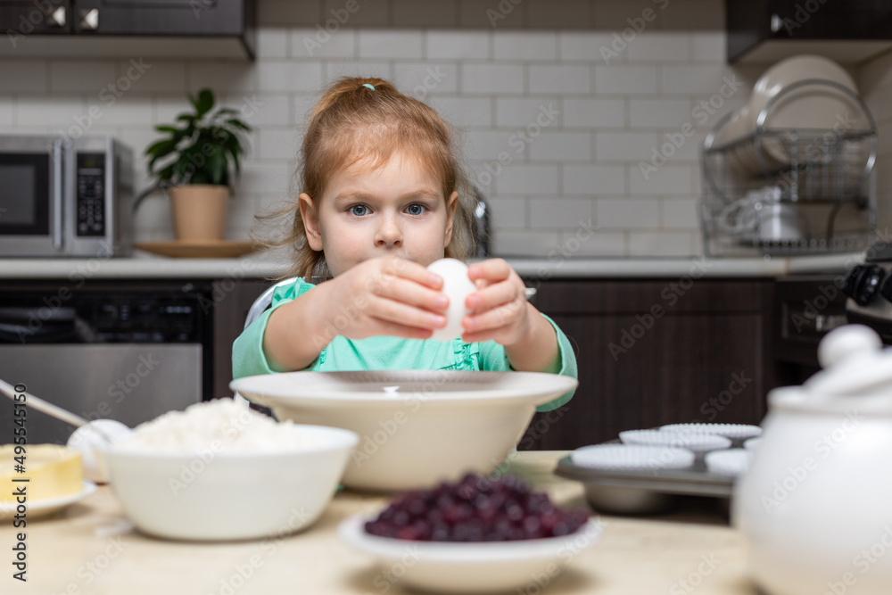 Little girl cooking in kitchen. Child sitting at table with food. Kid baking at home Little girl cooking in kitchen. Child sitting at table with food. Kid baking at home