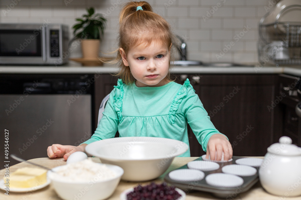 Little child learning to cook muffins. Small girl helping in kitchen. Kid ready to mix ingredients Little child learning to cook muffins. Small girl helping in kitchen. Kid ready to mix ingredients