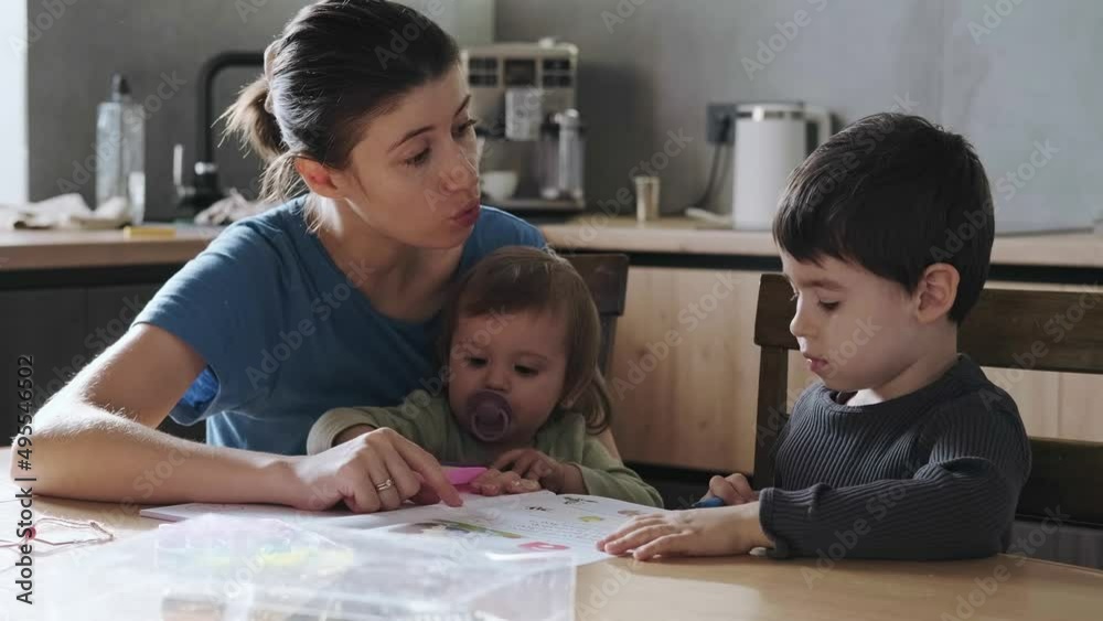 Mother doing homework with her son pointing to something written in his notebook and correcting him. Social distancing and self isolation in quarantine lockdown Mother doing homework with her son pointing to something written in his notebook and correcting him. Social distancing and self isolation in quarantine lockdown