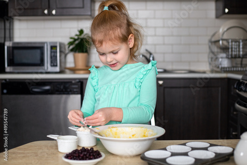 Little girl learning to cook making dough for muffins. Small child cooking in kitchen. Homemade food