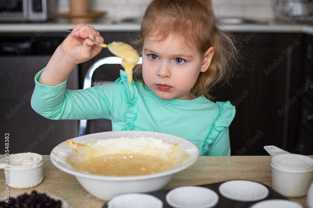 Small child cooking in kitchen. Little beautiful girl making dough for muffins at home. Small child cooking in kitchen. Little beautiful girl making dough for muffins at home.