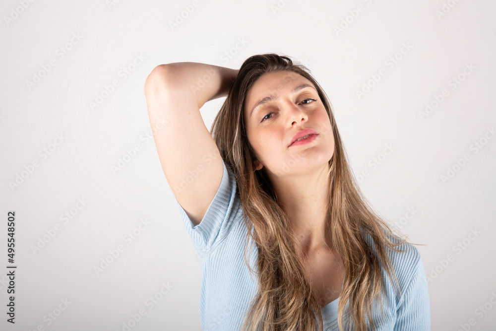 Portrait of a young blond woman with a sensual expression, with one hand behind her head