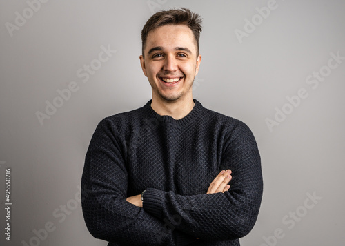 Portrait of one adult caucasian man 25 years old looking to the camera in front of white wall background smiling wearing casual black sweater copy space photo