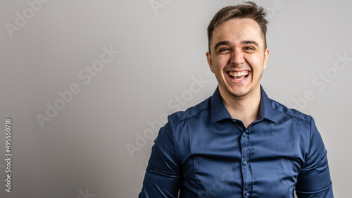 Portrait of one adult caucasian man 25 years old looking to the camera in front of white wall background smiling wearing casual blue shirt copy space © Miljan Živković