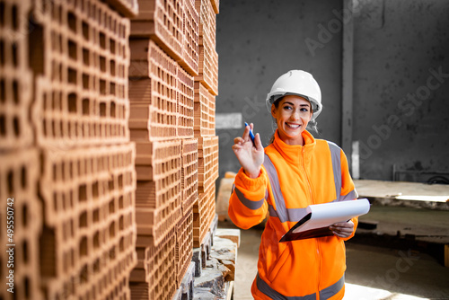 Industrial female worker checking inventory of bricks ready to dispatch to the construction site.
