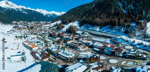 Ski resort town of St. Anton am Arlberg in Austria with amazing winter sunny sky and snowy mountains covered with pine trees in the background photo