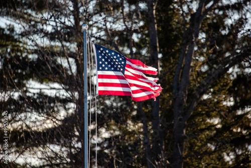 Badly tattered American flag flying from flagpole outside